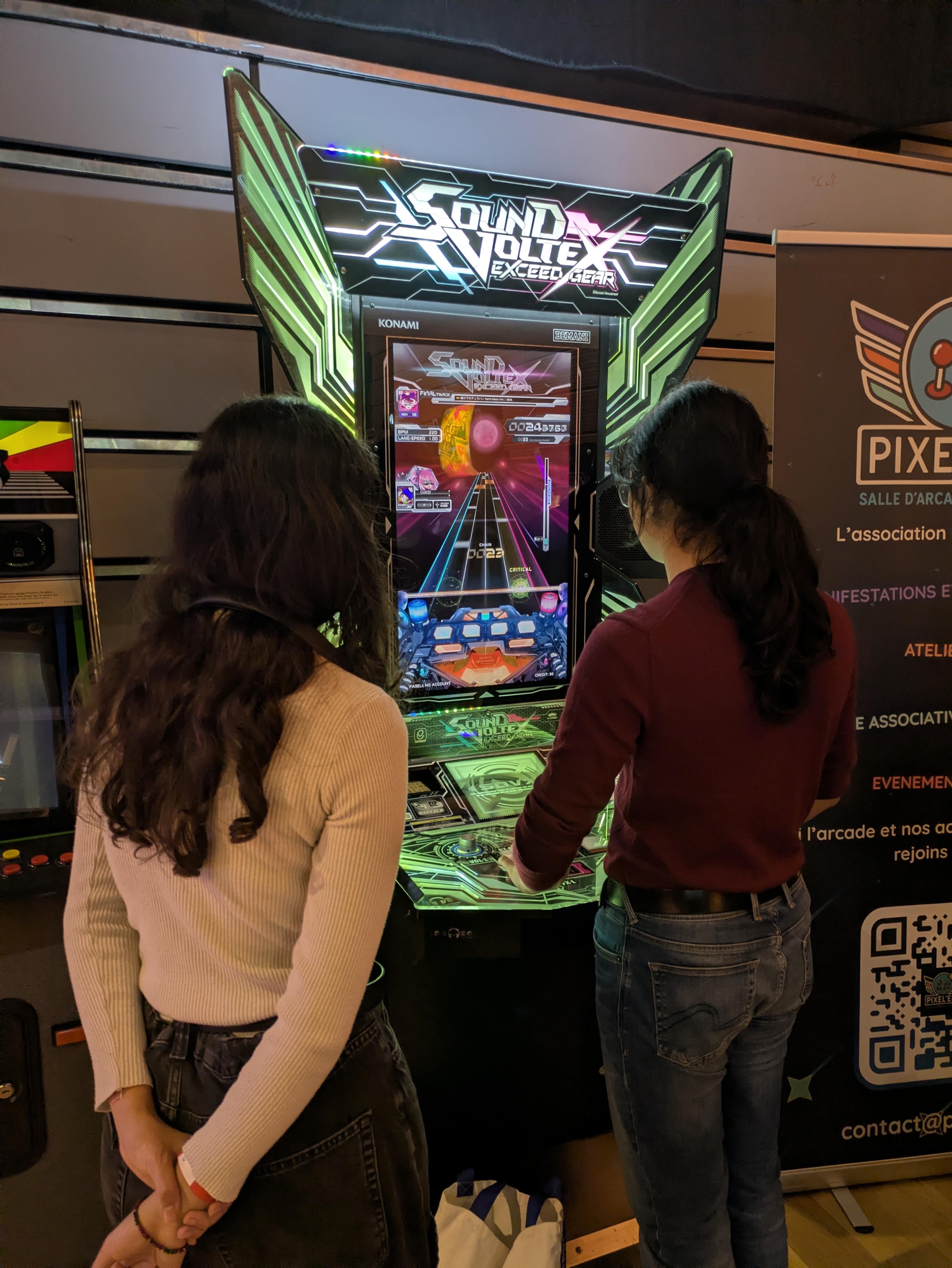 Deux personnes découvrant le jeu Sound Voltex